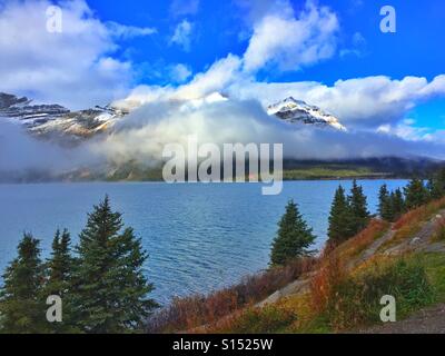 Mattino Nuvoloso al Lago di prua con pochi colori autunnali nella per la terra e per i vacanzieri di un lodge in lontananza Foto Stock