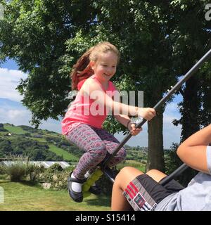 Ragazza giovane giocando su swing Foto Stock