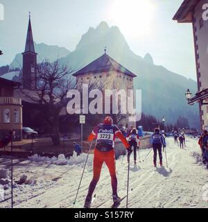 L'uomo sci sci di fondo corsa Marchia Longa attraverso città attornoal Dolomiti nelle Alpi Italiane Foto Stock