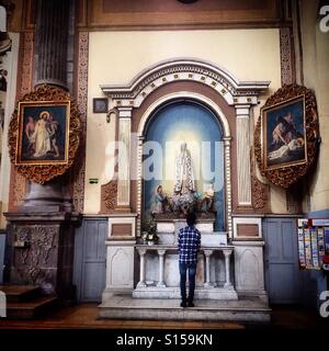 Un giovane uomo che prega di Nostra Signora di Fatima a La Compañía Templo del Espiritu Santo, in Puebla de Zaragoza, Messico Foto Stock