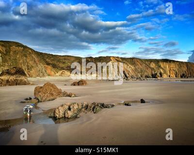 Un giovane ragazzo suona in una rock pool su Marlowes sands beach in Galles del Sud Foto Stock