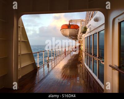 Guardando indietro lungo il ponte della Queen Mary 2 al tramonto sull'Atlantico dopo il brutto tempo Foto Stock