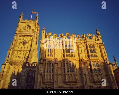 Un inizio di mattina autunno immagine della Chiesa Parrocchiale di San Giovanni Battista a Cirencester, Gloucestershire, Inghilterra. La Union Jack Flag è in volo e il cielo è blu. Credito foto - © COLIN HOSKINS. Foto Stock
