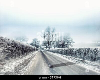 Vista del conducente attraverso il parabrezza auto della strada in inverno. Estrema la brina e il ghiaccio. Vicino a Sherborne, Dorset, Inghilterra. Foto Stock