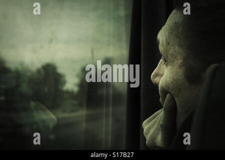 L'uomo sul bus guardando fuori della finestra, il dito sulla guancia Foto Stock