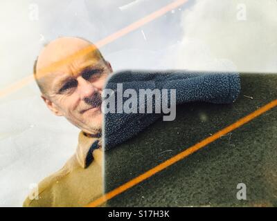 La riflessione di un medioevo l uomo nel finestrino posteriore di una vettura in possesso di un telefono cellulare Foto Stock