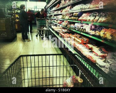 POV spingendo il carrello per supermercati giù il corridoio di formaggio in un supermercato spagnolo Foto Stock