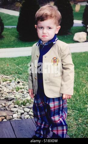 Un ritratto di un bimbo piccolo ragazzo vestito con una tuta facendo una faccia comico Foto Stock