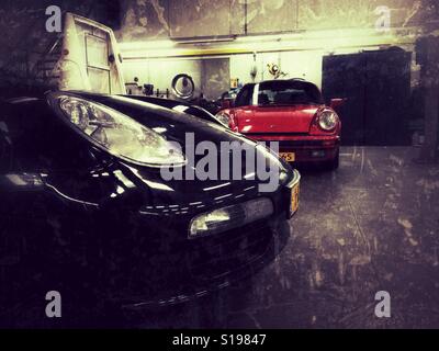 Due bolidi porsche in un workshop in piedi su un pavimento Concreat Foto Stock