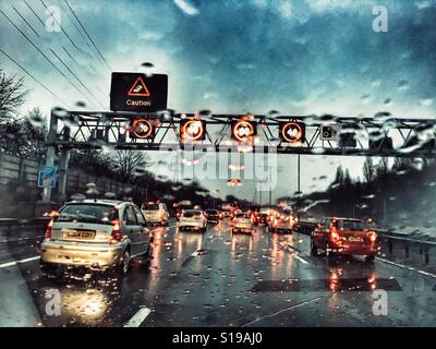 La guida su M6, Smart Motrway sotto la pioggia. Overhead gantry con limitazioni di velocità e consigli Foto Stock