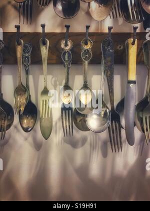 Coltelli e forchette e cucchiai appeso a una parete della cucina Foto Stock