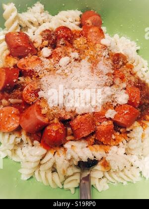 La pasta con la salsa di pomodoro,pezzi di salsiccia e formaggio grana padano in una ciotola verde e la forcella all'interno Foto Stock