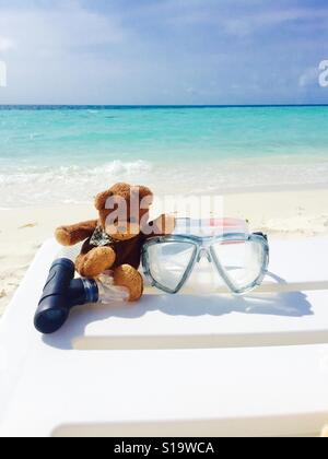 Orsacchiotto di peluche seduto sulla sedia spiaggia con attrezzatura snorkeling, Maldive Foto Stock