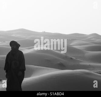 L'uomo nel Sahara con i cammelli in background Foto Stock