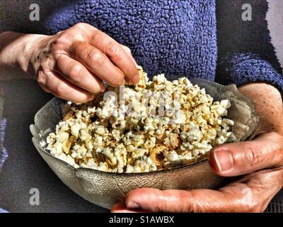 Donna che mantiene una ciotola di popcorn, close up delle mani Foto Stock