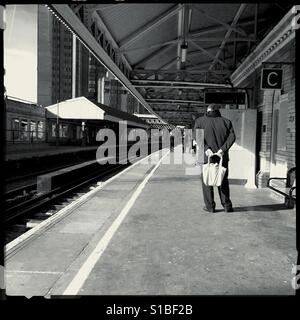 L'uomo tenendo un sacco sulla stazione ferroviaria platform Foto Stock