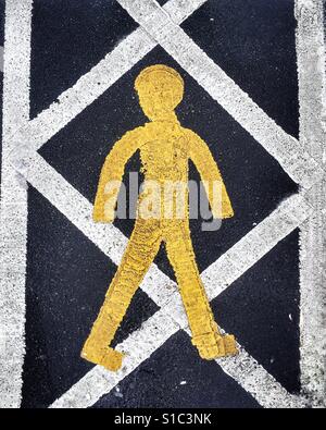 Giallo e bianco verniciato marcatura stradale segno raffigurante il un bastone giallo figura su un sicuro pedonale percorso a piedi. Foto Stock