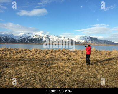 Un uomo di prendere una fotografia in western Islanda Foto Stock