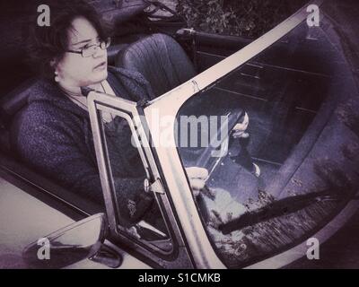 Giovane donna alla guida di un 1973 MGB Roadster con il cofano verso il basso. Foto Stock