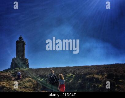 La famiglia in cammino verso il Giubileo a Darwen Torre a Darwen Moor retroilluminati da Sun Foto Stock