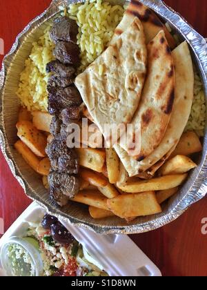 La cucina greca per andare. Agnello souvlaki stick su patatine fritte e riso con pita e insalata sul lato di andare come servita da Cozmos Gyro in Nepean, Ontario, Canada, 13 aprile 2017. Foto Stock