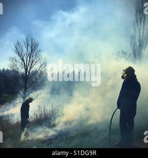 Due persone in marcia sicurezza facendo una combustione controllata di un campo in Minnesota, Stati Uniti d'America. Foto Stock