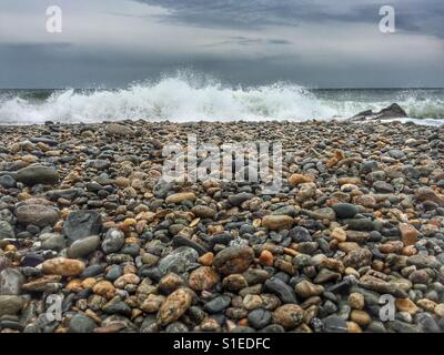 Onda di rottura sulla spiaggia ghiaiosa Foto Stock