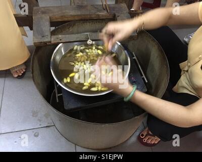 Fabbrica di seta. Hoi An, Vietnam. Bollito di bozzoli di seta. Foto Stock