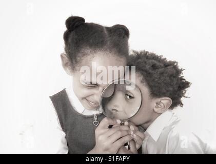 Kids guardando attraverso una lente di ingrandimento. Foto Stock