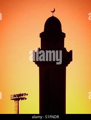 Il sole tramonta dietro una moschea in Qatar Foto Stock
