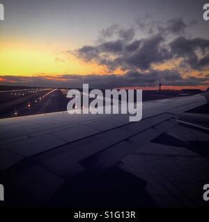 Vista dall'aereo prima di decollare con colorati cielo durante il tramonto in background. Foto Stock