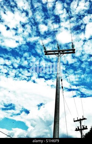 I pali dell'elettricità sotto il cielo nuvoloso Foto Stock
