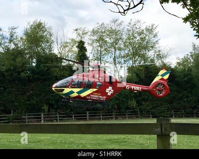 La Thames Valley Air Ambulance terre in un campo di Oxfordshire per il trasporto di un ferito in ospedale. Foto Stock