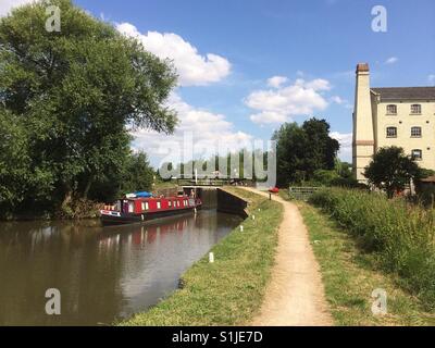 Narrowboat passando attraverso un blocco sulla navigazione Stort a Parndon Mill, Harlow, Essex. Vecchio mulino edifici in background. Foto Stock