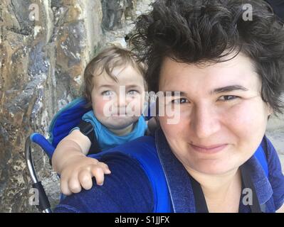 Donna sorridente con il suo figlio in carrier Foto Stock