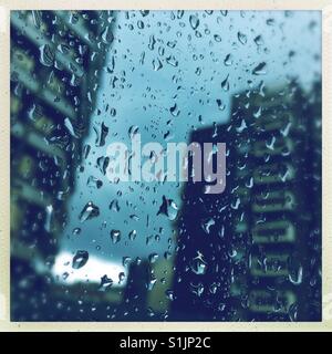 Gocce di pioggia su una finestra con edifici in background Foto Stock