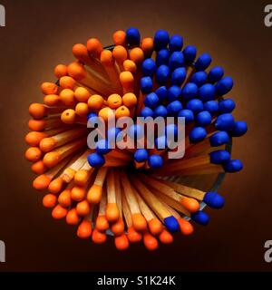 Un overhead shot di un mazzetto di blu e arancio dei fiammiferi con punta in un contenitore di vetro Foto Stock