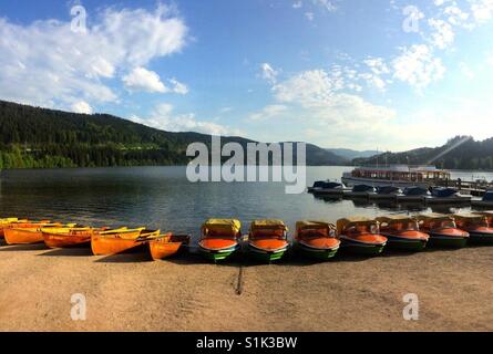 Una fila di barche colorate linea le rive di un lago Foto Stock