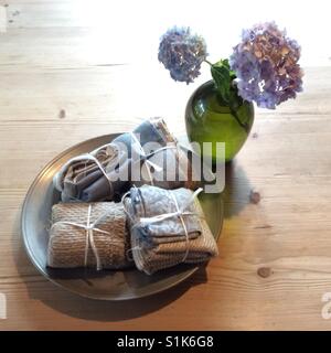 Biancheria Vintage sulla vecchia piastra di stagno e la fioritura delle ortensie blu sul tavolo di legno Foto Stock