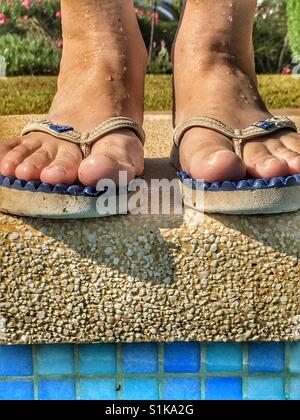 In piedi al bordo della piscina. Piedi in flipflops, basso angolo di visione Foto Stock