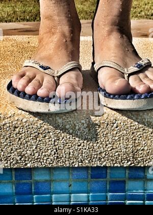 In piedi al bordo della piscina. Piedi in flipflops, basso angolo di visione Foto Stock