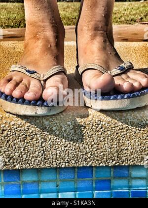 In piedi al bordo della piscina. Piedi in flipflops, basso angolo di visione Foto Stock