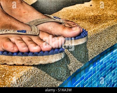 In piedi al bordo della piscina. Piedi in flipflops, basso angolo di visione Foto Stock