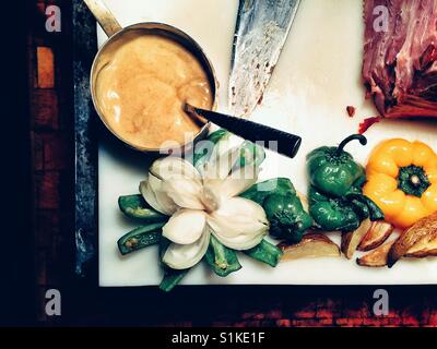 Cipolla bianca tagliata come fiore e presentati su un peperone verde accanto alla carne e salsa in pentola di rame Foto Stock