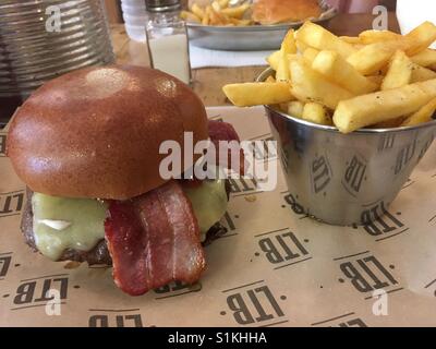 Bacon cheeseburger e patatine fritte al rosmarino. Foto Stock