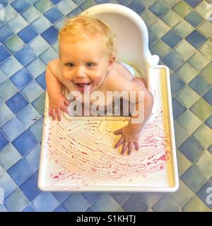 Undici mesi di età bambino seduto in un confuso sedia alta Foto Stock