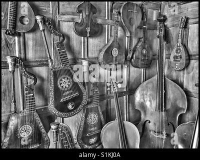 Un'immagine monocromatica che mostra una collezione di strumenti a corda in pannelli di legno angolo di una casa di campagna. Arpa, violini & chitarre sono visibili. Credito foto - © COLIN HOSKINS. Foto Stock