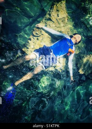 L'uomo galleggianti in chiare acque del lago il Kayangan su Coron Island nelle Filippine Foto Stock