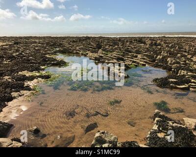 Newton Bay, Porthcawl, Galles - Agosto 2917: un rock pool a bassa marea riflette il Cielo di estate Foto Stock