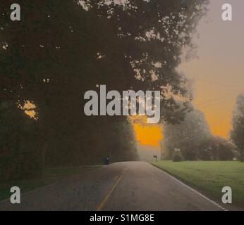 Foto con look colorizzato- mattina bagliore nel cielo sopra strada di avvicinamento parte superiore della collina nelle zone rurali del Nord Carolina Foto Stock